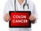 Doctor showing tablet with COLON CANCER text