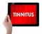 Doctor showing tablet with TINNITUS text.