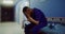 A doctor sits on a medical gurney and rubs his head in empty hospital corridor