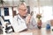 Doctor sitting at desk in office. Man is looking at broccoli with magnifying glass.