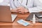 Doctor sitting at his desk with laptop, notes, face mask and pills