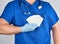 doctor in sterile latex gloves and blue uniform holds a blank white business card