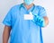 Doctor in sterile latex gloves and blue uniform holds a blank white business card