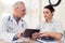 Doctor with stethoscope and female patient in office. Doctor is using tablet.