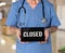 Doctor with stethoscope in medical scrubs holding electronic tablet saying hospital is closed