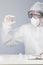 Doctor with surgical mask and protective clothing looking at a vaccine