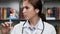 Doctor and syringe. Concentrated woman doctor in white coat in office holds disposable syringe filled with solution in