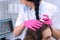 Doctor trichologist examines woman patient`s hairs using trichoscope in clinic.