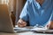 Doctor in uniform of doctor using digital technology laptop for Output Device and writing a patient report on the office desk.