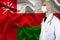 Doctor in uniform with a stethoscope on the background of the silk national flag of Oman, the concept of medical care in the