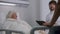Doctor uses digital tablet, consults elderly woman in hospital room