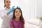 Doctor using lice treatment spray on girl`s hair indoors