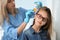 Doctor using nit comb and spray on girl`s hair. Anti lice treatment
