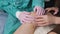 A doctor wearing medical gloves examines the injured knee of a female patient.