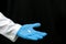 A doctor in a white coat holds a pill in his hand on a black background. Medical preparations for the treatment of coronavirus. A