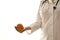 Doctor in a white coat stands with an outstretched hand and demonstrates a whole orange of her hand. With a stethoscope