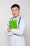 A doctor in a white coat with a stethoscope on his neck holds a green folder in his hands. One on a white background