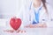 Doctor in white coat with stethoscope holding pills and plastic heart  on white