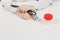 Doctor at white desk with bottle white pills in office in hospital. Woman holds in hands stethoscope in consulting room