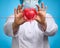 Doctor in a white medical coat holding a red heart. Cardiovascular disease concept, early diagnosis. Blue background