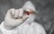 Doctor in white protective suit, medical mask and rubber gloves is holding a red pill as a medications from coronavirus