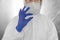 Doctor in white protective suit, medical mask and rubber gloves is holding a white pill as a medications from