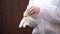 The doctor in white suit puts protective gloves on white background; protection against coronavirus COVID-19