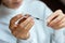 Doctor in a white surgical gown and blue mask holds in hands a medical syringe and bottle with insulin for diabetes. Sugar