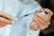 Doctor in a white surgical gown and blue mask holds in hands a medical syringe and bottle with insulin for diabetes. Sugar