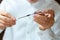 Doctor in a white surgical gown and blue mask holds in hands a medical syringe and bottle with insulin for diabetes. Sugar