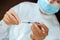 Doctor in a white surgical gown and blue mask holds in hands a medical syringe and bottle with insulin for diabetes. Sugar