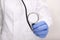 A doctor in white uniform and blue rubber gloves holding stethoscope close up, professional expertise and testing