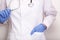 A doctor in white uniform and blue rubber gloves holding stethoscope, professional expertise and testing concept