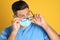 Doctor wiping foggy glasses caused by wearing medical mask on yellow background