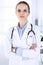 Doctor woman headshot at work in hospital. Physician standing straight and smiling, studio portrait. Medicine and health