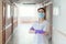 Doctor a woman in a lab coat, medical mask and gloves poses in a hospital corridor with her arms crossed over her chest.The