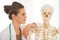 Doctor woman looking on human skeleton