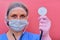 Doctor woman in medical mask on a red background with a stethoscope in his hand. Medic struggling with lung diseases, coronavirus