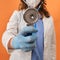 Doctor woman in medical mask on a red background with a stethoscope in his hand. Medic struggling with lung diseases, coronavirus