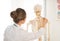 Doctor woman teaching anatomy using human skeleton