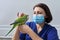Doctor woman veterinarian examining a green Quaker parrot