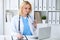 Doctor woman at work. Portrait of cheerful smiling blonde physician using tablet computer while sitting at the desk