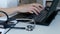 Doctor working on a computer, keyboard close up. Stethoscope on a table