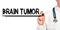 Doctor writes the word - BRAIN TUMOR. Image of a hand holding a marker isolated on a white background