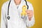 Doctor with yellow ribbon on color background, closeup. Cancer awareness concept