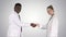 Doctors shaking hands and posing to camera on gradient background.