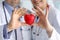 Doctors in white coats hold heart, focus on heart.