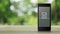 Document flat icon on modern smart mobile phone screen on wooden table over blur green tree in park, Business communication online