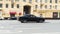 Dodge Challenger GT in black color driving fast on the street of Moscow. Sunny summer day in city. Speeding on urban highway road