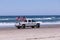 Dodge pickup truck with two American flags and two boys in a trunk driving on a beach